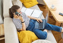 Eine Frau mit Telefon und Laptop auf einem Sofa - Christin Klose/dpa-tmn/dpa