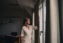 Frau schaut aus einem Fenster - Zacharie Scheurer/dpa-tmn