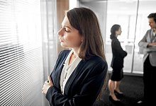 Frau steht abseits ihrer Kollegen in einem B&uuml;ro - Klaus-Dietmar Gabbert/dpa-tmn