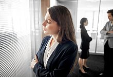 Frau schaut nachdenklich durch die Scheibe eines Konferenzraums - Klaus-Dietmar Gabbert/dpa-tmn