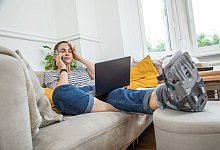 Eine Frau mit einem Gehgips am Fuss auf einer Couch - Christin Klose/dpa-tmn