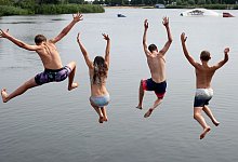 Kinder springen in einem See - Ronny Hartmann/dpa-tmn