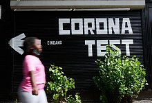 &laquo;Corona Test&raquo; und ein Richtungspfeil steht auf einer Garage w&auml;hrend eine Person vor&uuml;ber geht. Corona-B&uuml;rgertests f&uuml;r alle sollen k&uuml;nftig drei Euro kosten. - Annette Riedl/dpa