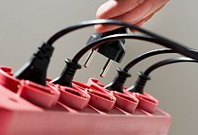 Ein Mann zieht einen Stecker aus einer Steckerleiste - Franziska Gabbert/dpa-tmn