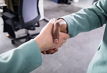 Zwei Personen reichen sich in einem Büro die Hand - Christin Klose/dpa-tmn