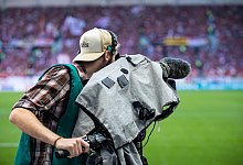 Ein Kameramann steht am Spielfeldrand und filmt ein Fußballspiel. - Tom Weller/dpa