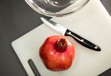 Granatapfel liegt neben einem Messer auf einem Tisch - Christin Klose/dpa-tmn