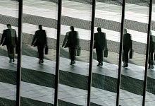 Mann spiegelt sich in den Glasscheiben eines Büros - Oliver Berg/dpa/dpa-tmn