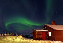 Gr&uuml;nes Nordlicht am Nachthimmel &uuml;ber einem Haus. - Andrea Warnecke/dpa-tmn