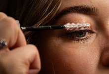 Frau tuscht sich die Wimpern mit Glitzer-Mascara - Christin Klose/dpa-tmn