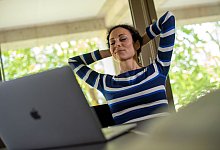 Frau sitzt entspannt an einem Schreibtisch - Klaus-Dietmar Gabbert/dpa-tmn