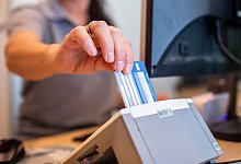 Eine Frau liest eine Versichertenkarte aus - David Inderlied/dpa/dpa-tmn