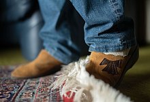 Seniorin bleibt beim Gehen an einem Teppich hängen - Nicolas Armer/dpa/dpa-tmn