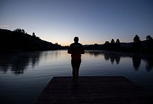 Ein Mann steht auf einem Steg an einem See - Marijan Murat/dpa/dpa-tmn