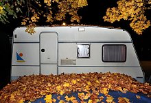 Ein Wohnwagen hinter Herbstlaub - Karl-Josef Hildenbrand/dpa/dpa-tmn
