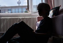 Ein Kind liest an eine Couch gelehnt - Annette Riedl/dpa/dpa-tmn