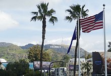 Eine US-Flagge vor Palmen und dem Hollywood-Schriftzug - Barbara Munker/dpa/dpa-tmn