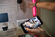 Eine Frau steuert mit einem Smartphone eine Ueberwachungskamera - Zacharie Scheurer/dpa-tmn