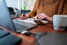 Frau sitzt mit einem Laptop am Tisch - Fabian Strauch/dpa/dpa-tmn