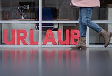 Eine Frau läuft an den Buchstaben Urlaub vorbei - Sebastian Kahnert/dpa/dpa-tmn