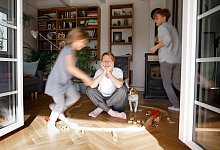 Gestresste Mutter sitzt zwischen dem Spielzeug ihrer Kinder - Katharina Mikhrin/Westend61/dpa-tmn