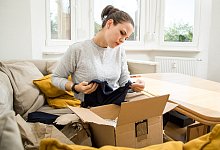 Eine Frau packt ein Paket aus - Christin Klose/dpa-tmn