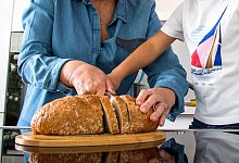 Zwei Menschen schneiden Brot - Christin Klose/dpa-tmn