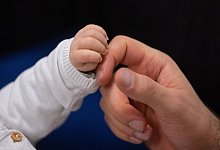 Hand eines Babys und eines Erwachsenen - Marijan Murat/dpa