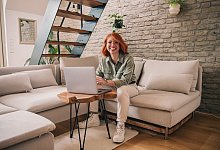 Eine Frau am Laptop sitzt auf einem Sofa - Zacharie Scheurer/dpa-tmn