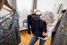 Frau probiert schwarzes Oberteil an - Christin Klose/dpa-tmn