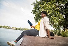 Frau entspannt mit einem Buch am See - Christin Klose/dpa-tmn