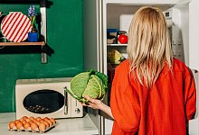 Eine Frau h&auml;lt einen Kohl vor einem offenen K&uuml;hlschrank - Vira Simon/Westend61/dpa-tmn