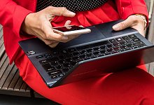 Eine Frau hält ein Smartphone und ein Laptop in den Händen - Christin Klose/dpa-tmn/dpa