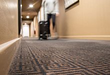 Eine Person mit einem Koffer einem Hotelflur - Christin Klose/dpa-tmn