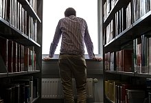 Ein Mann steht am Fenster einer Bibliothek - Markus Scholz/dpa-tmn