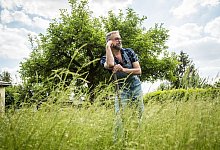 Ein Mann steht mit einem Spaten im Garten - Christin Klose/dpa-tmn