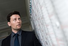 Mann schaut besorgt auf einen Wandkalender - Alexander Heinl/dpa-tmn