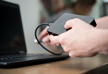 Eine Frau schliesst eine externe Festplatte an einem PC an - Henrik Josef Boerger/dpa/dpa-tmn