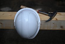 Bauhelm und Zimmermannshammer auf einer Baustelle - Soeren Stache/dpa/dpa-tmn