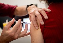 Ein Arzt impft eine Patientin gegen die Grippe - Zacharie Scheurer/dpa-tmn