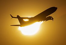 Flugzeug vor der Sonne - Boris Roessler/dpa