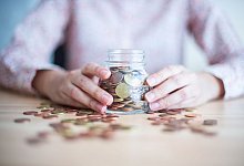 Eine Frau hält ein mit Münzen gefülltes Glas - Arne Immanuel Bänsch/dpa/dpa-tmn