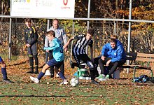 Einsatz im Herbstlaub auf dem Kunstrasenplatz: Werl-Aspes Alexander Löwen (rechts) setzt sich im C-Junioren-Spiel gegen Lemgos Andreas Fot durch. Im Hintergrund TBV-Trainer Lars Schrahe, auf der Bank: Christian Schulze (Fitnesstrainer). - Kai Hahn