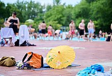 Handtücher und Rücksäcke liegen am Beckenrand eines Freibads - Annette Riedl/dpa/dpa-tmn