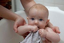 Person h&auml;lt Baby in Badewanne - Silvia Marks/dpa-tmn