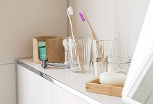 Badezimmer-Ablage mit Zahnb&uuml;rsten in Bechern - Christin Klose/dpa-tmn