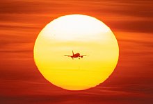 Ein Flugzeug vor untergehender Sonne - Boris Roessler/dpa/dpa-tmn