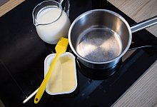 Butter, Milch und ein Topf stehen auf einem Herd - Christin Klose/dpa-tmn