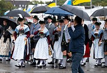 Eine Trachtengruppe geht nach dem traditionellen Trachten- und Sch&uuml;tzenzug mit Regenschirmen &uuml;ber das Oktoberfestgel&auml;nde. - Sven Hoppe/dpa