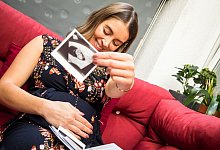 Eine schwangere Frau zeigt ein Ultraschallbild. - Christin Klose/dpa-tmn